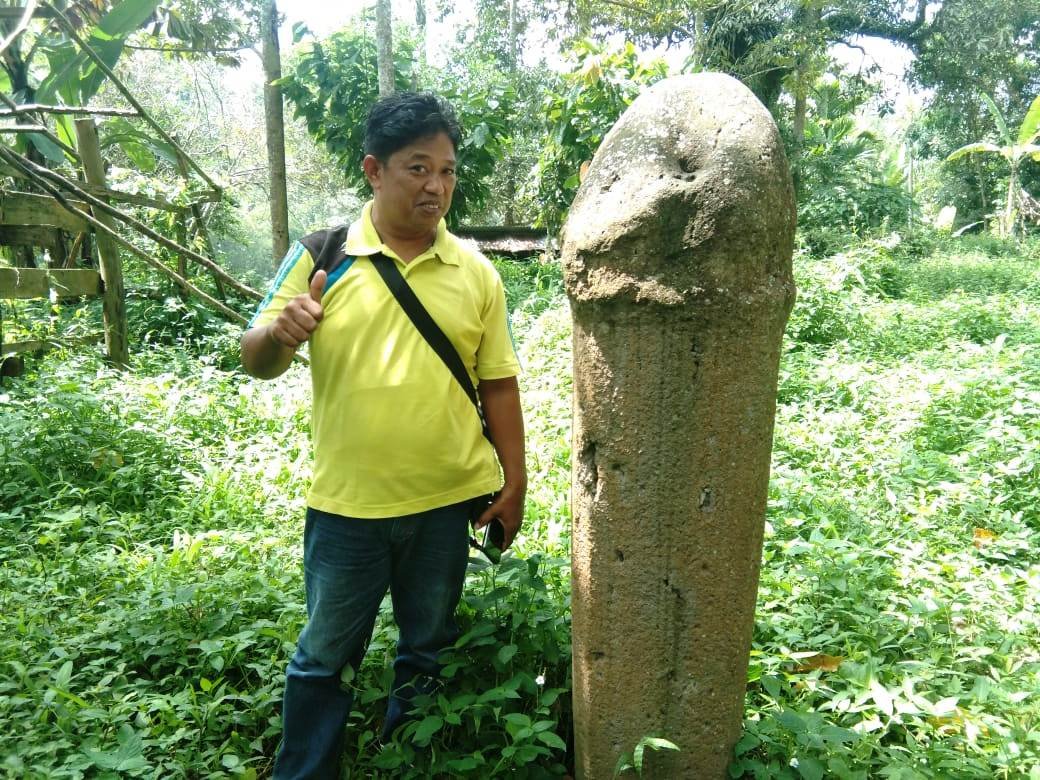 Salah satu warga Tanah Datar berfoto di samping batu prasasti berbentuk alat kelamin yang ditemukan di Nagari Tanjung Tanah Datar Sumbar (M Rafi / Mattanews.co)